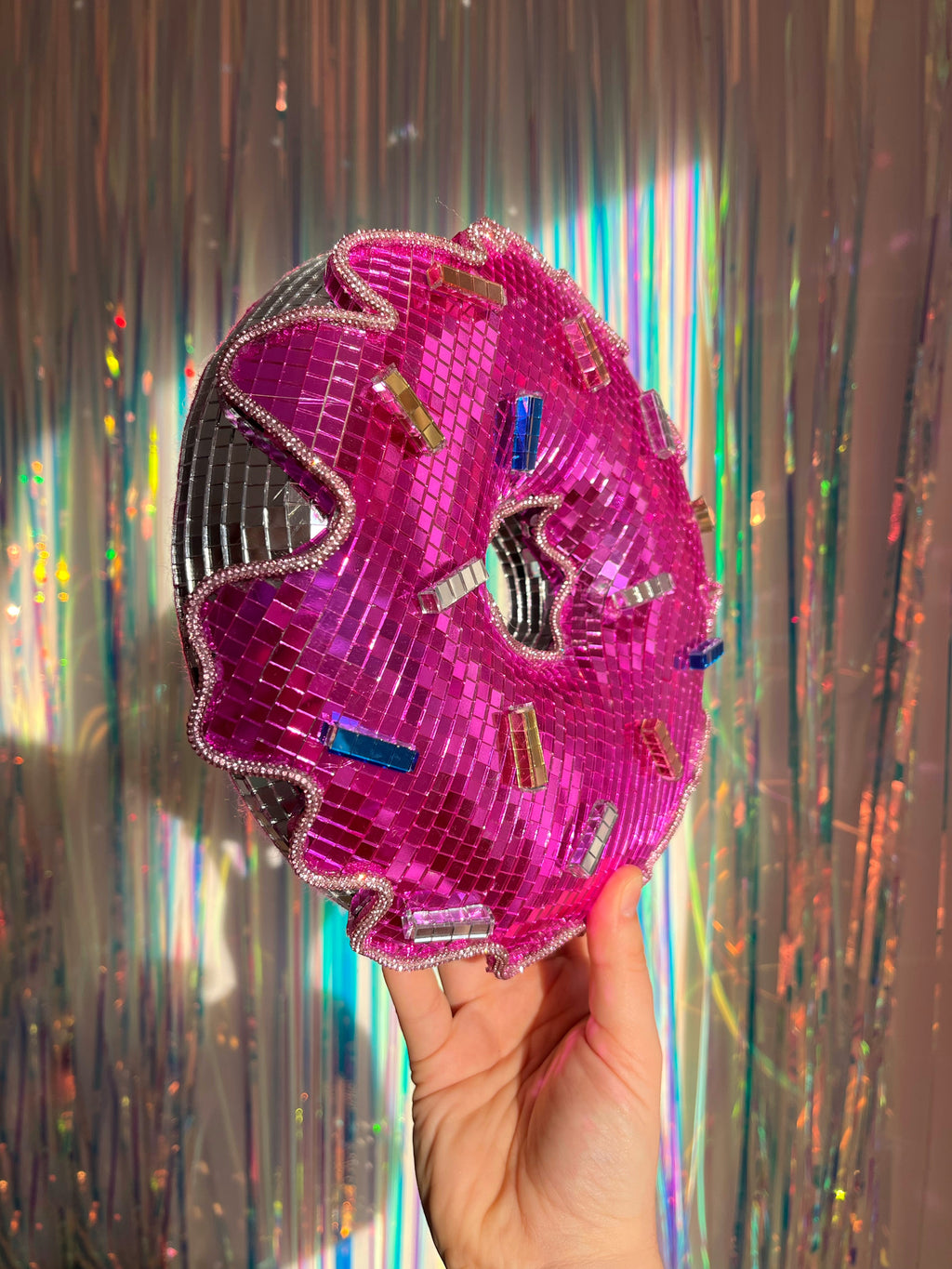 Pink disco ball donut being held up by a hand. Town Girl Disco